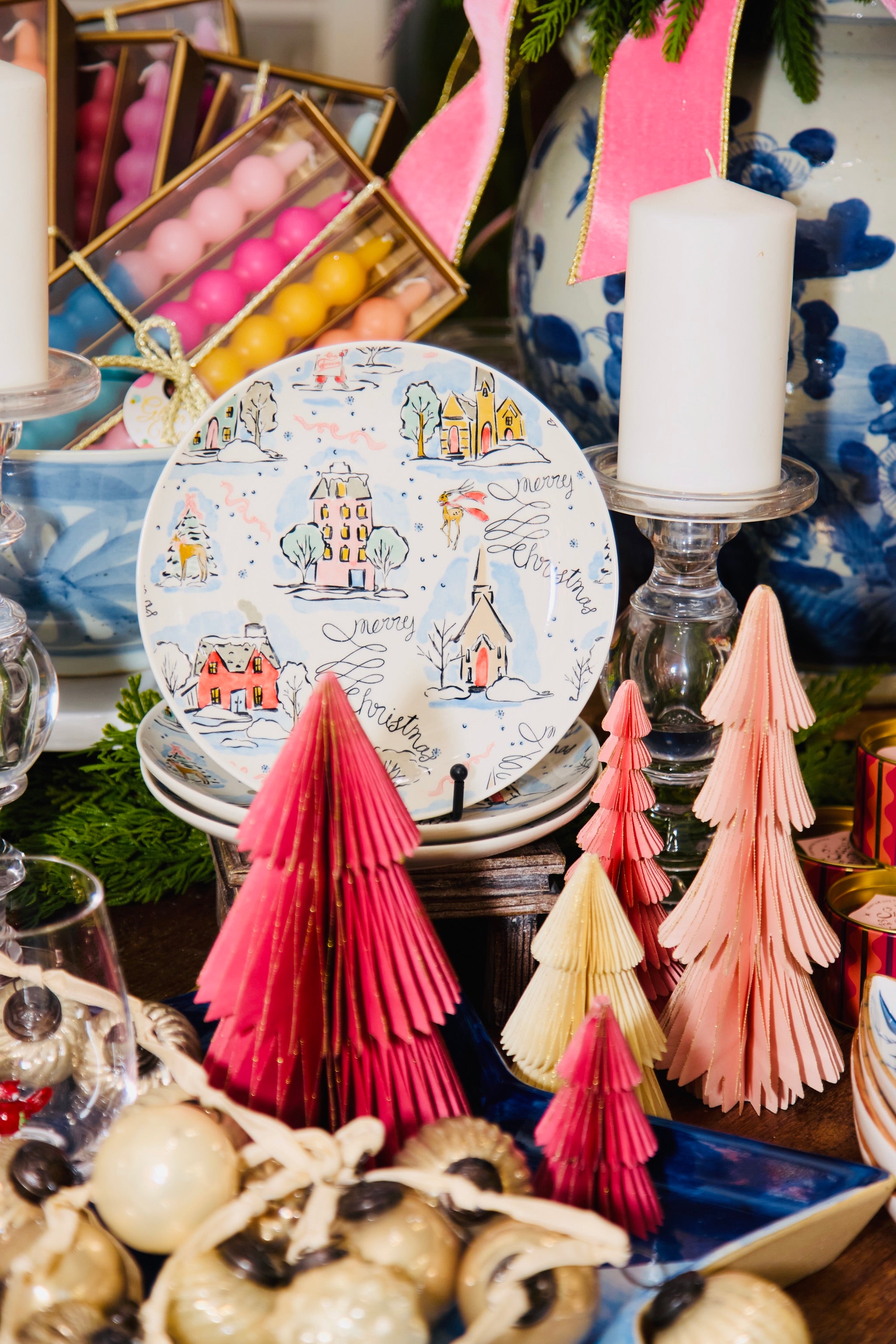Decorative table setting with a plate, candles, and paper trees.
